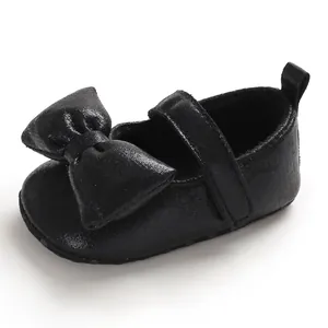 Close-up of elegant black baby girl princess shoes with large bow and soft non-slip sole.