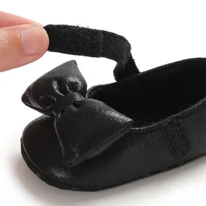 Macro view of black baby princess shoe featuring bow detail and adjustable velcro strap