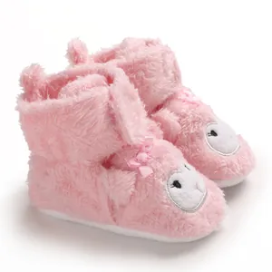 Dettaglio di scarpe da neonato in peluche rosa con simpatico viso di animale e fiocco