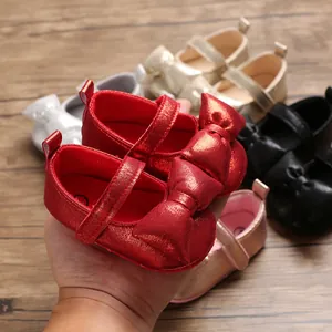 Detailed view of shiny red metallic baby girl princess shoes with a large decorative bow.