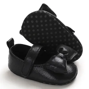 Close-up of the decorative black bow and glittery texture on soft-soled princess baby shoes
