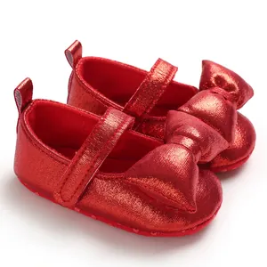 Close-up of metallic red baby princess shoes with oversized bow and soft sole
