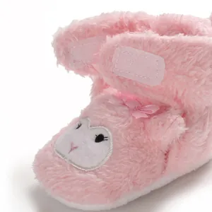 Dettaglio scarpe neonato in peluche rosa con simpatico musetto e consistenza molto soffice