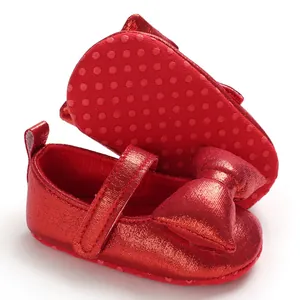 Close-up of red shiny baby princess shoes with bow and anti-slip soft sole