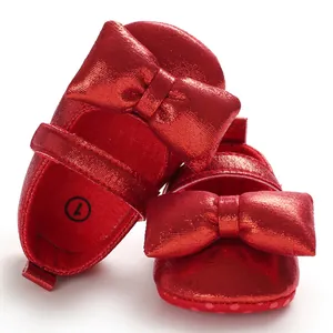 Macro view of metallic red baby princess shoes featuring decorative bow and Velcro strap