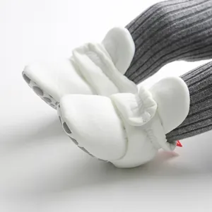 Close-up detail of white soft-sole baby walker booties featuring an anti-slip bottom