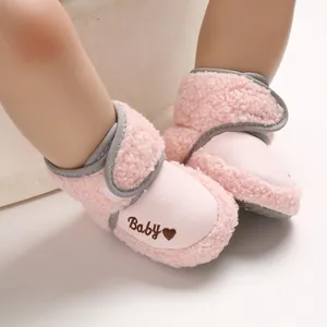 Close-up of pink plush baby snow boots with soft fleece lining and heart embroidery