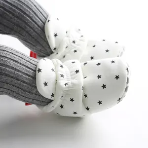 Close-up detail of white baby booties with black star patterns and soft grip soles