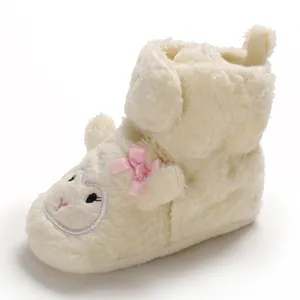 Primo piano di scarpine primi passi in soffice peluche bianco con fiocco rosa carino