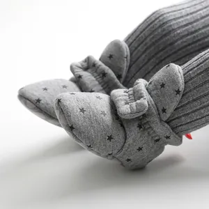 Macro view of grey baby soft-soled sock shoes with star pattern and flap detail.