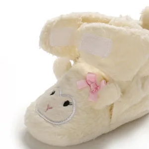 Dettaglio della scarpa primi passi in peluche con ricamo a pecora e fiocco rosa
