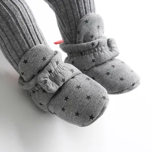 Close-up detail of grey baby pre-walker sock shoes with black star pattern and soft texture