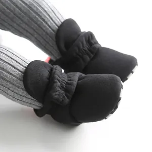 Close-up of black baby soft-sole walking shoes with elastic ankles and stripe detail.