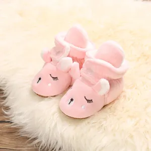 Primo piano di scarpine rosa in peluche per neonati con design cartoon su tappeto.