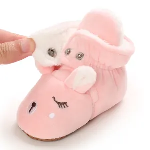 Dettaglio di stivaletti rosa in peluche per neonati con viso carino e bottone