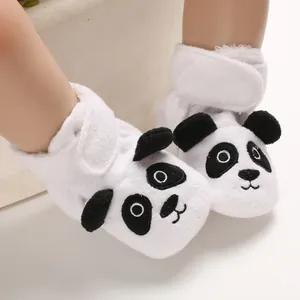 Dettaglio ravvicinato di morbide scarpine per neonati in peluche bianco con motivo panda