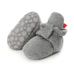 Close-up of soft grey knit baby booties featuring non-slip soles and adjustable closures