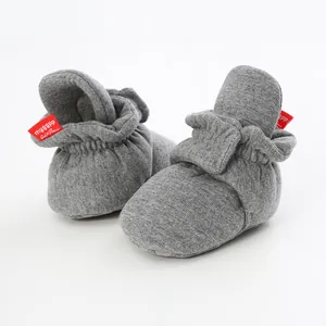 Detail of grey infant sock shoes with soft soles and velcro straps for baby walkers.