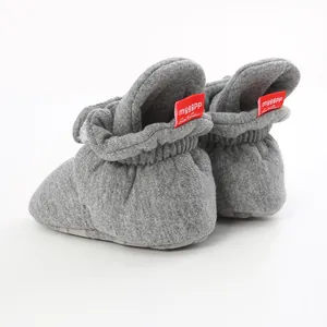 Close-up detail view of grey cotton baby booties with soft soles and distinct red tags