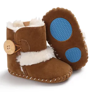 Detail view of brown baby snow boots with white fur trim and blue non-slip soles.