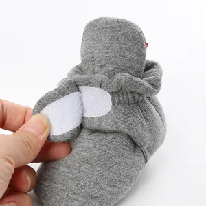 Detailed view of the white hook-and-loop closure on a soft grey knit baby pre-walker shoe