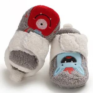 Close-up of fuzzy baby booties with cute embroidered cartoon monster details and soft fleece.
