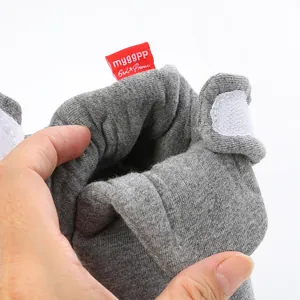 Macro detail view of soft grey knitted baby sock shoes with a red woven brand tag