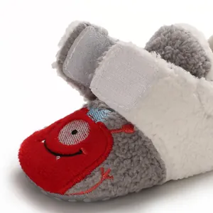 Close-up of soft plush baby winter shoe featuring a red cartoon monster embroidery