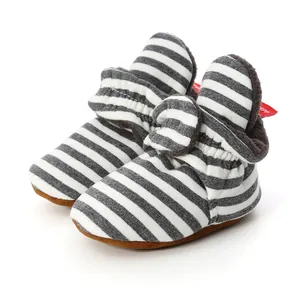 Close-up of striped knit baby booties with soft brown soles and warm fleece lining