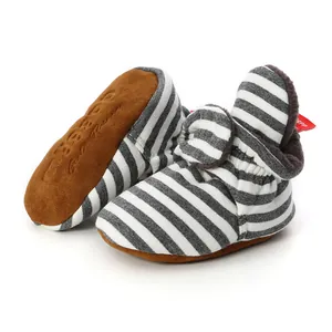 Close-up of striped knitted baby booties featuring soft brown anti-slip suede soles