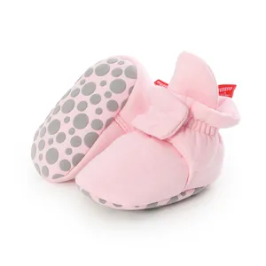 Close-up view of pink soft-sole infant booties featuring anti-slip dotted bottom.