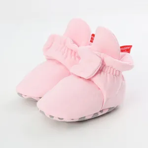 Close-up of pink soft sole baby shoes featuring a bow detail and anti-slip dots on the bottom.