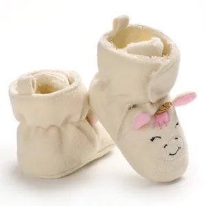 Dettaglio ravvicinato di scarpine neonato unicorno in peluche morbido per l'inverno.