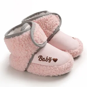 Close-up detail of pink sherpa baby winter boots with velcro and embroidered heart