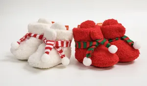 Close-up of soft red and white fleece baby Christmas booties with striped scarf detail