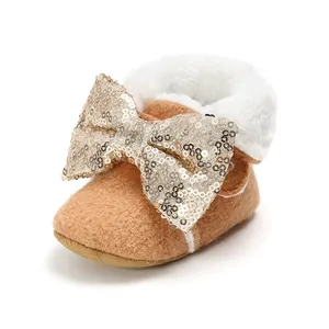 Warme braune Baby-Winterschuhe mit großer goldener Paillettenschleife und weißem Fellbesatz