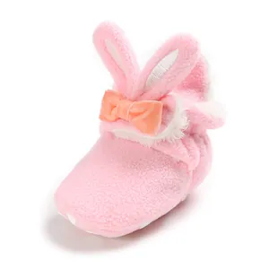 Detail van roze babyboots met konijnenoren, zachte fleece en oranje strik voor baby's