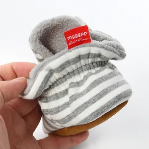 Macro view of striped baby sock shoe featuring soft fleece lining and red brand tag