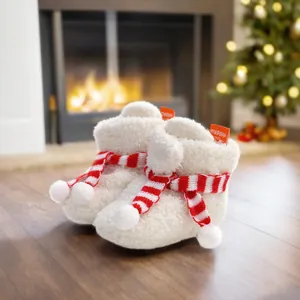 Detail of white plush baby Christmas boots featuring a cozy red striped scarf accent