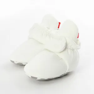 Detail of white soft-sole baby booties featuring anti-slip grip and elastic ankle