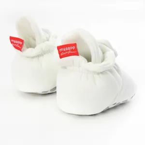 Rear view of comfortable white baby booties featuring a soft sole and red brand tag