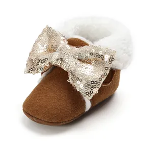 Nahaufnahme eines braunen Baby-Winterstiefels mit weißem Pelz und goldener Paillettenschleife