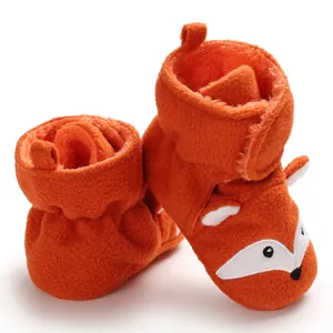 Dettaglio delle scarpine neonato in peluche arancione con viso di volpe a fumetti