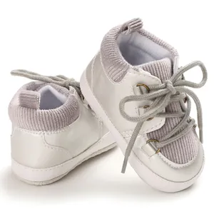 Vue détaillée de chaussures de marche blanches pour bébé avec velours côtelé gris et semelles.