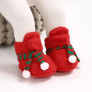 Detailed close-up of red plush Christmas baby boots with festive scarf and pom-poms