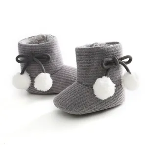 Vue détaillée de bottines en tricot gris pour bébé avec pompons blancs et doublure