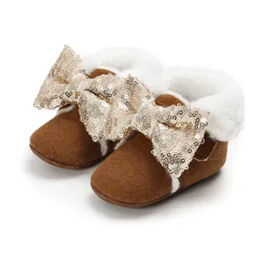 Detailansicht brauner Baby-Winterstiefel mit weißem Kunstfell und einer goldenen Paillettenschleife.