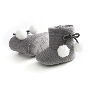 Bottes de bébé tricotées grises avec pompons blancs et semelles souples antidérapantes