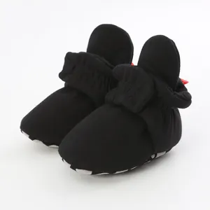 Close-up view of black cotton baby booties featuring soft soles and elasticized ankles