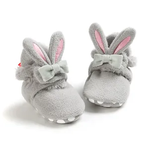 Detailopname van pluche grijze babyschoentjes met konijnenoren, zachte zool en een strikje